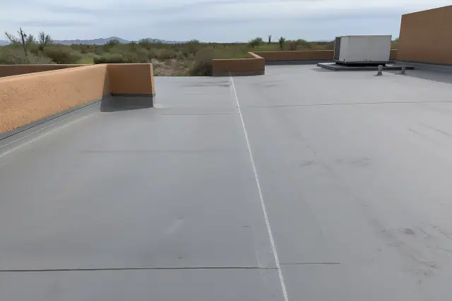 Heat-welded seam on a gray membrane roof with desert scrub and stucco parapet walls in Tucson, AZ.