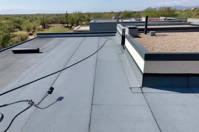 Heat-welded seams on a flat-roof membrane with prickly pear cacti in the background in Tucson, AZ.