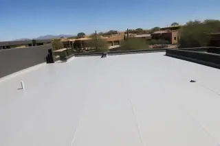 Finished flat membrane roof with sealed seams on a stucco building in Tucson, AZ, surrounded by desert landscaping.