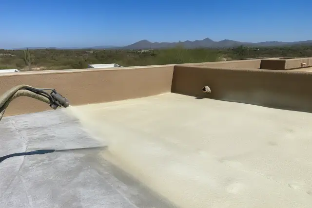 Polyurethane foam being sprayed over an existing roof during a project in Tucson, AZ.