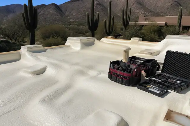 Technician tool kit on a finished foam roof with saguaro cacti in the background in Tucson, AZ.