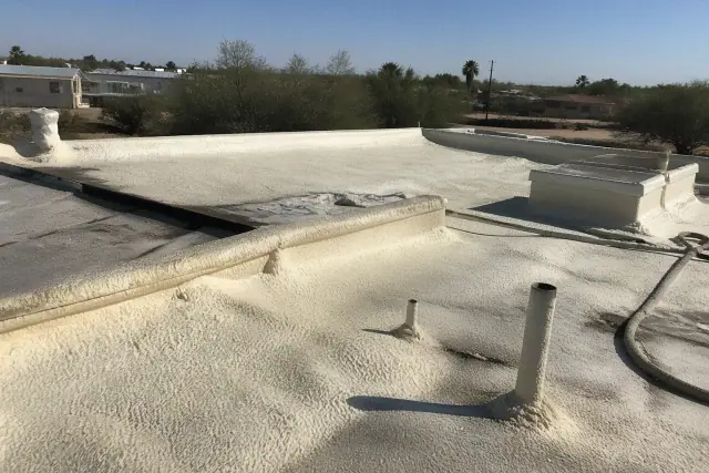 Worker applying polyurethane foam insulation to a residential roof in Flowing Wells, AZ.