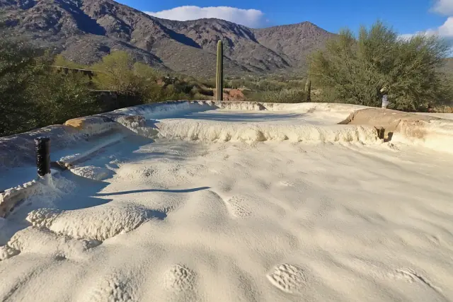 Polyurethane foam insulation being sprayed onto a roof in Catalina Foothills, AZ, with a mountain backdrop.