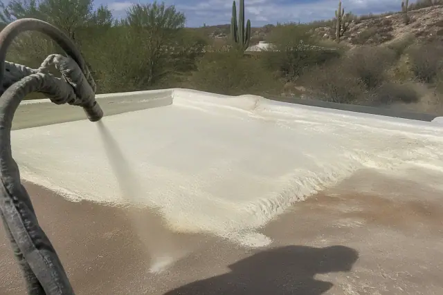 A contractor applying spray polyurethane foam roofing to a desert substrate in Green Valley, AZ.