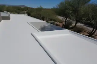White foam roof coating on a flat commercial building with desert xeriscaping in Tucson, AZ.