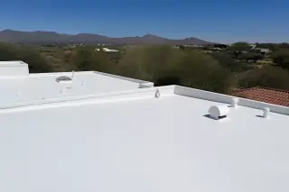 Smooth white elastomeric foam finish on a residential roof with Sonoran desert landscape in Tucson, AZ.