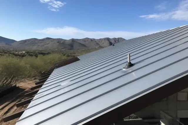 Galvalume and G-90 standing seam metal panels being installed on a sloped roof frame in Tucson, AZ.