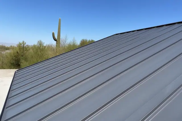 Standing seam metal roof installation on a commercial building under bright desert sun in Tucson, AZ.