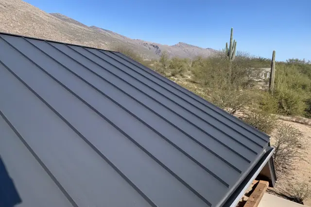 Standing seam metal roof panels installed on a sloped frame with saguaro cacti in the background in Tanque Verde, AZ.