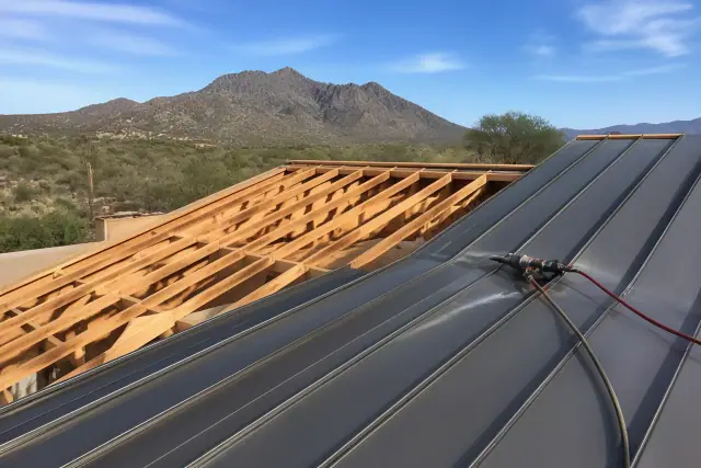 Standing seam metal roof panels being installed on a sloped framework in Green Valley, AZ.