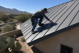 Technician inspecting vertical standing seam metal panels and clean edges on a Tucson, AZ roof with prickly pear cacti.