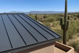 Standing seam metal roof panels with sharp ridge trim and saguaro cacti in the background in Tucson, AZ.
