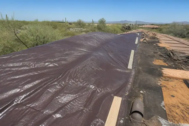 Heavy-duty reinforced tarp secured over a damaged roof section after a monsoon storm in Tucson, AZ.