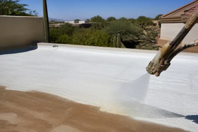 Contractor applying polyurethane foam roofing to a building in Tucson, AZ with desert landscaping in the background.
