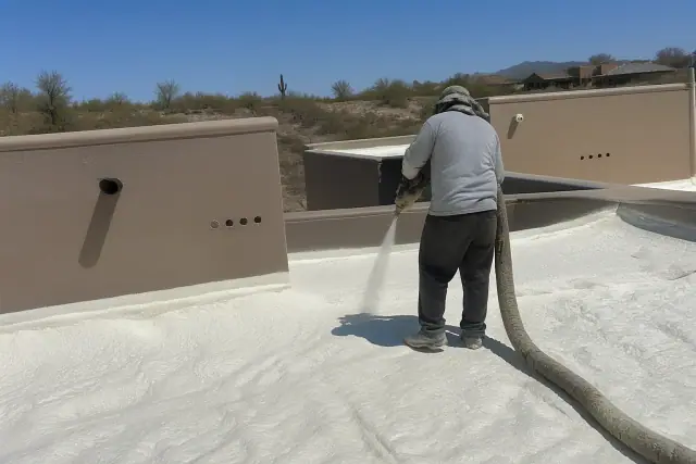 Contractor spraying polyurethane foam insulation on a residential rooftop in Tucson, AZ.