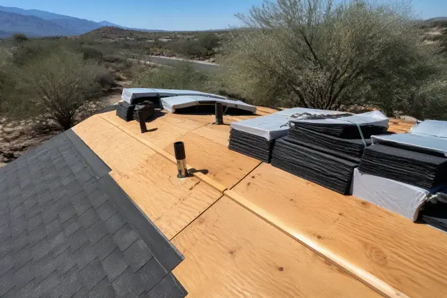 Technician securing shingle bundles to a sloped residential roof during a project in Tucson, AZ.