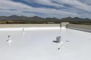 White reflective roof coating on a commercial building with stucco parapets and mountain views in Tucson, AZ.