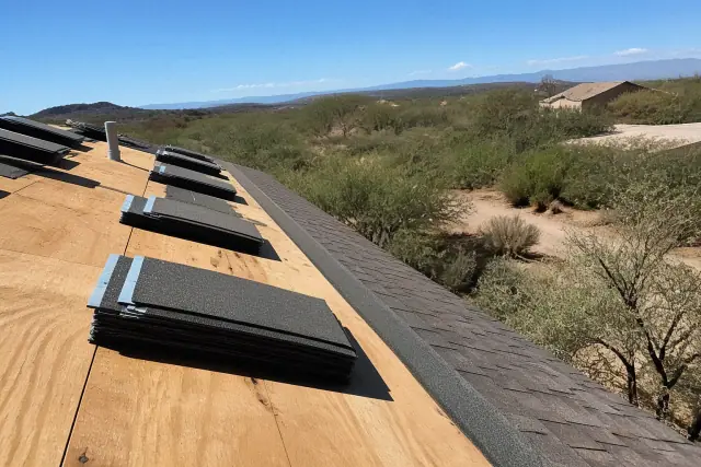 A technician kneeling on a steep shingled roof while installing materials at a jobsite in Sahuarita, AZ.