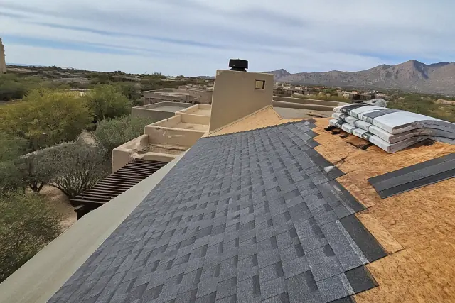 Technician installing new asphalt shingles on a sloped roof in Casas Adobes, AZ.