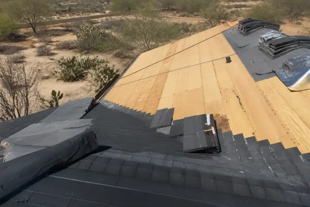 Technician installing shingles on a steep-sloped roof in Marana, AZ with prickly pear cacti in the desert landscape.