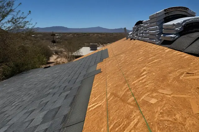 Technician installing shingles on a steep roof in Drexel Heights, AZ with desert landscape in the background.