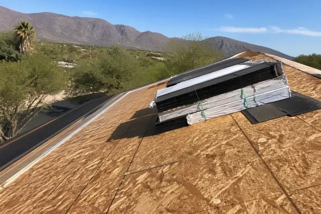 Bundles of shingles secured to a residential roof during a project in Tanque Verde, AZ, with desert mountains in view.