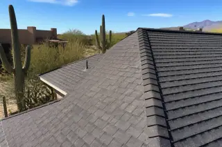 Cleanly installed asphalt shingles and ridge caps on a pitched roof under bright desert sun in Tucson, AZ.