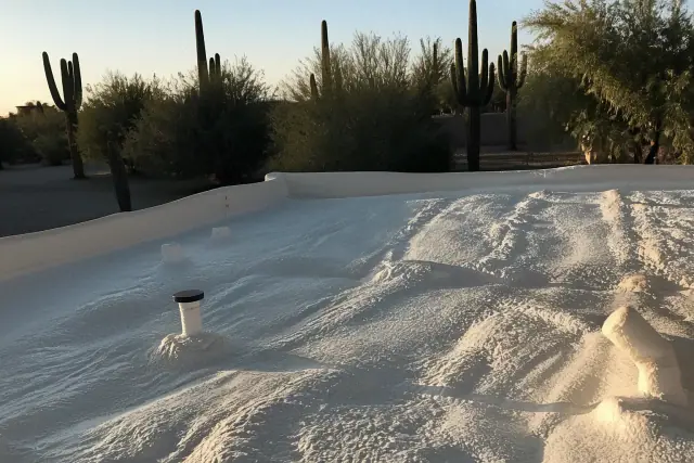 Freshly applied silicone elastomeric coating on a flat foam roof with desert landscaping in Tucson, AZ.