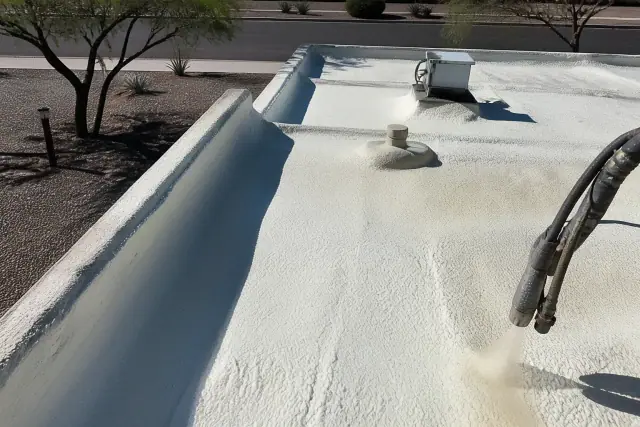 Operator applying spray polyurethane foam insulation to a commercial roof in Tucson, AZ.