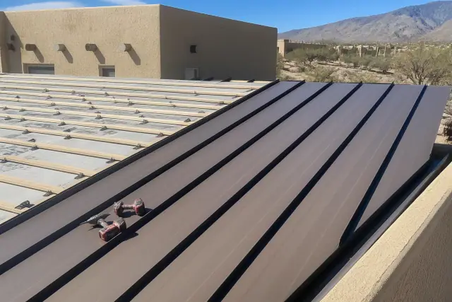 Standing seam metal panels being installed on a sloped roof at a job site in Tucson, AZ.