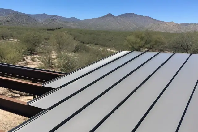 Standing seam metal panels being installed on a sloped roof in Tucson, AZ, with desert mountains in the background.