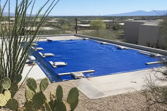 Temporary emergency tarp secured with sandbags and wood battens on a damaged flat roof in Tucson, AZ.