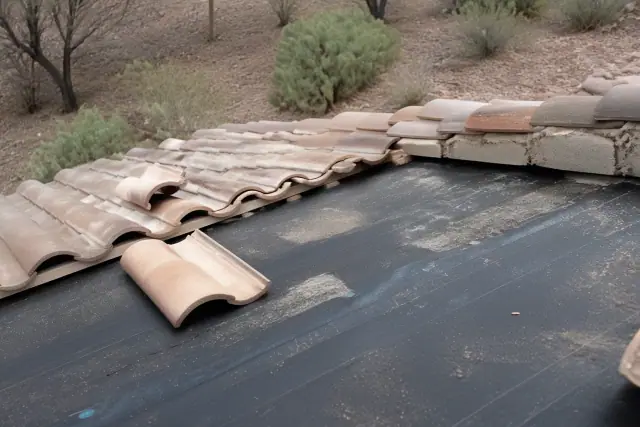 Contractor removing clay roof tiles to inspect the underlayment during a repair in Drexel Heights, AZ.