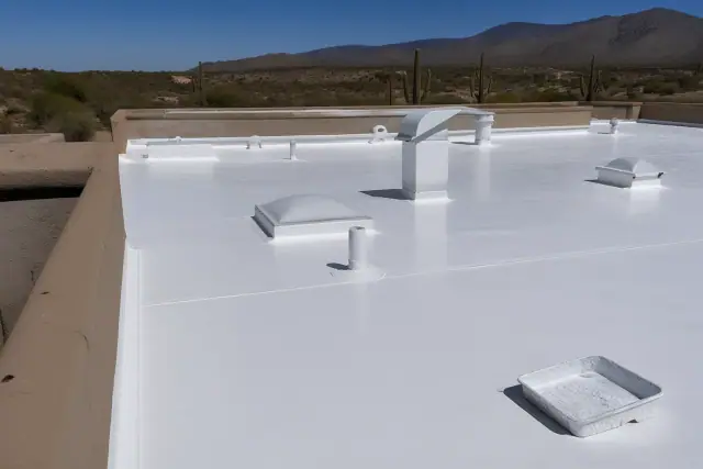 Completed white reflective roof coating on a commercial building with stucco parapets and desert views in Tucson, AZ.