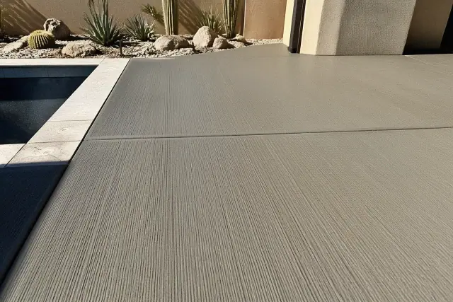Freshly cured broom-finished concrete pool deck with parallel traction grooves in Tucson, AZ, near desert landscaping.