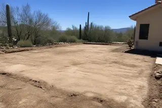 Cleared and leveled dirt ground where a pool deck was removed, surrounded by saguaro cacti in Tucson, AZ.