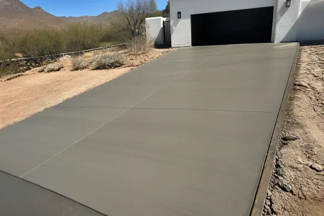 Newly installed concrete driveway with a textured finish and surrounding desert landscape in Drexel Heights, AZ.