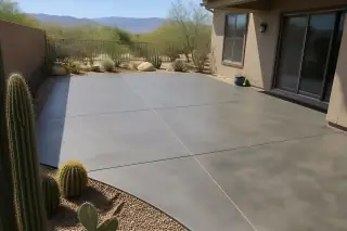 Finished concrete patio in a backyard with native cacti and stucco walls in Tucson, AZ.
