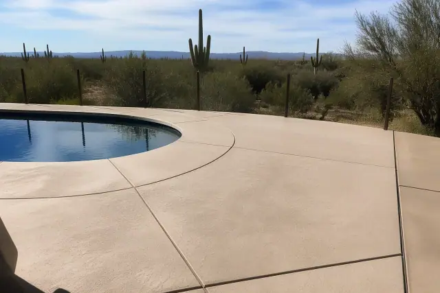 Newly installed concrete pool deck with expansion joints and saguaro cacti in the background in Tanque Verde, AZ.