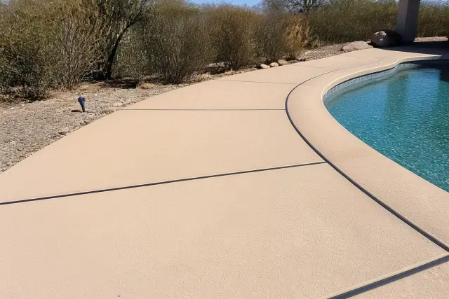 Concrete pool deck with dark flexible expansion joints in a residential backyard in Tucson, AZ.