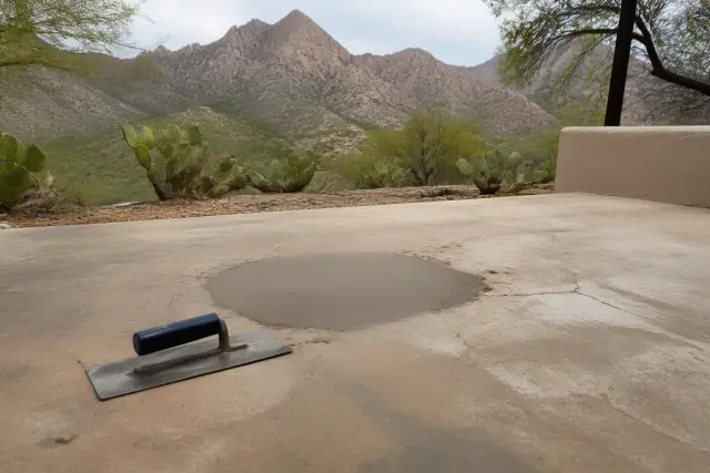 Trowel smoothing bonding compound into a concrete repair patch on a patio in Catalina Foothills, AZ.