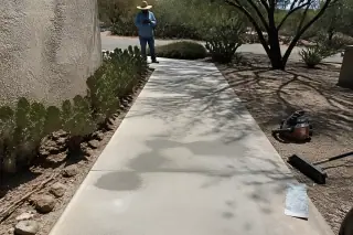 Cured concrete walkway patch with nearby tools and prickly pear cacti in a sunny Tucson, AZ residential yard.