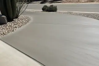 Patched and sealed concrete driveway surface with saguaro cacti in a sunny Tucson, AZ landscape.