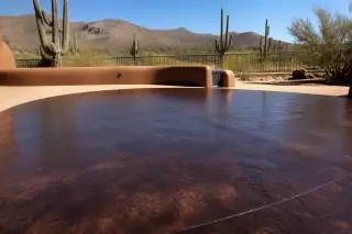 Deep-colored cured concrete surface with a uniform sheen near saguaro cacti in Tucson, AZ.