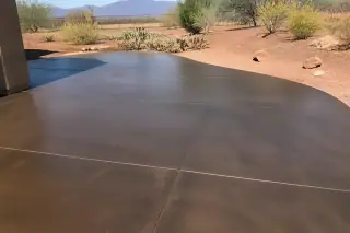 Sealed and cured concrete surface reflecting sunlight near prickly pear cactus in a Tucson, AZ desert landscape.
