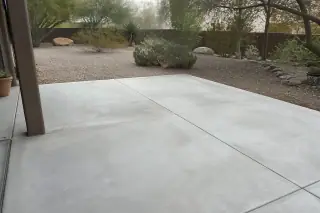 Finished concrete patio slab surrounded by prickly pear cacti and desert gravel in Tucson, AZ.