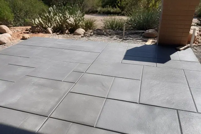 Control joints in an ashlar slate patio with prickly pear cactus in the background in Tucson, AZ.