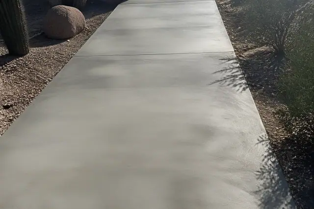 Contractor troweling a micro-topping skim coat onto a damaged concrete walkway in Tucson, AZ.