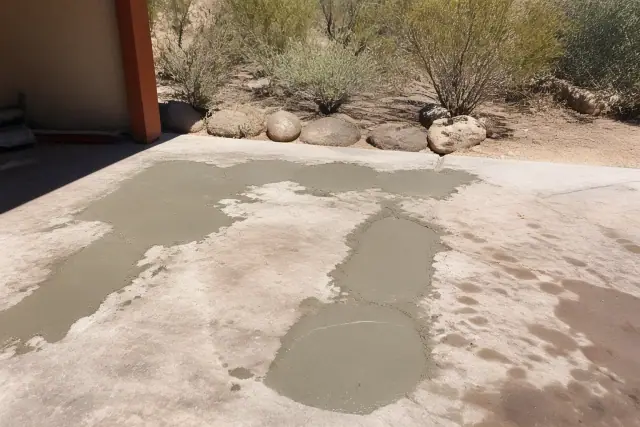 Freshly applied concrete repair compound with visible trowel marks on a slab in Tucson, AZ, surrounded by desert scrub.