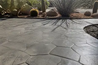 Gray stamped concrete patio with stone texture and wooden formwork in a Tucson, AZ desert landscape.